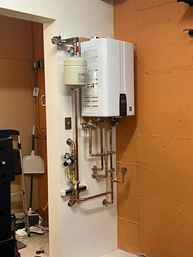 Plumbing technician inspecting water heater connections in Sandy
